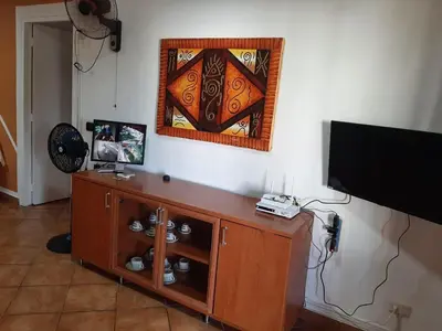 a living room with a tv and a wooden entertainment center at Palm Beach Resort in Boca Chica