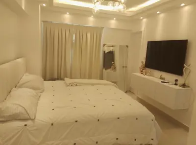 a white bedroom with a large bed and a television at Torre Sky 01 M10-2 in Santo Domingo
