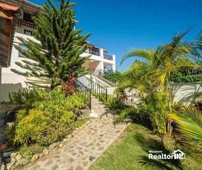 a house with a palm tree next to a walkway at Casa Estrella, Where Relaxation Begins in Sosúa