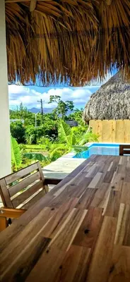a wooden table and a straw roofed table and chairs at Villa Turquesa En Dreams House - 5 pax, 2 min de la playa in Las Galeras