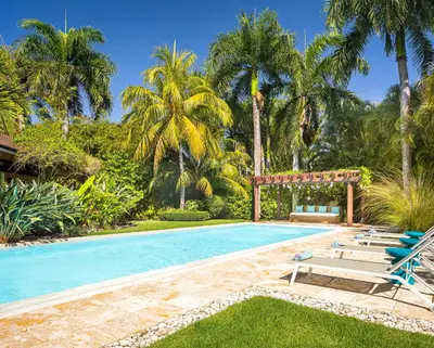 a swimming pool with lounge chairs and palm trees at Villa Maji Luxury Private Villa Steps from the Ocean Sea Horse Ranch Cabarete in Cabarete
