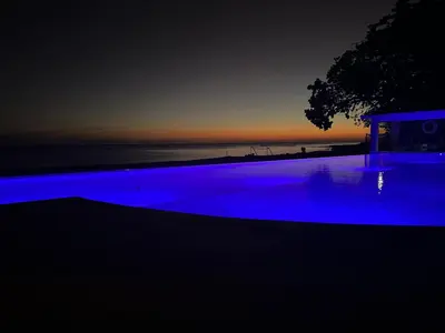 a swimming pool with blue lighting in front of the ocean at Villas Caribe in Juan Dolio