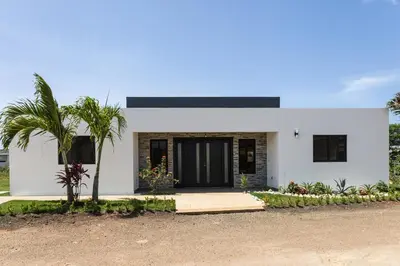 a white house with a palm tree in front of it at Bonita Extravaganza 4 Bedroom, 4 Bed, 3 Bedroom in Sosúa