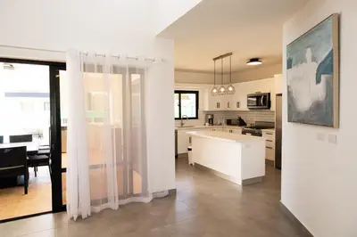 a kitchen and living room with white cabinets and a table at Bonita Extravaganza 4 Bedroom, 4 Bed, 3 Bedroom in Sosúa