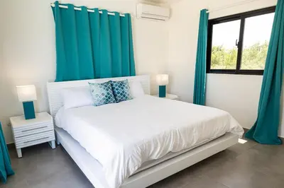 a bedroom with a white bed with blue curtains at Bonita Extravaganza 4 Bedroom, 4 Bed, 3 Bedroom in Sosúa