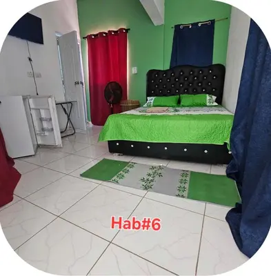 a bedroom with a bed with green sheets and red curtains at W&W Hotel in Las Terrenas