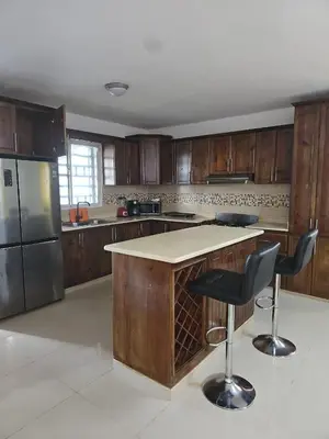 a kitchen with wooden cabinets and a island with bar stools at Naime 3 Bristol villa in San Pedro de Macorís