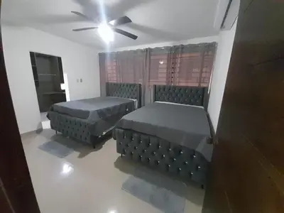 two beds in a room with a ceiling fan at Naime 3 Bristol villa in San Pedro de Macorís