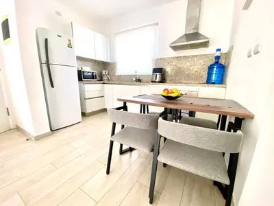 a kitchen with a wooden table with chairs and a refrigerator at Your Beautiful Village Central 5 Min from the Beach in Punta Cana