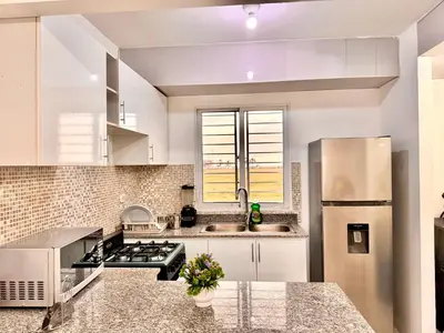 a kitchen with white cabinets and a stainless steel refrigerator at Ocean View Fast Wifi Close to Everything Coffee 2BR in La Cana