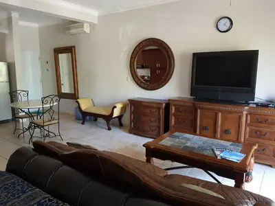 a living room with a couch and a flat screen tv at Cozy Garden Oasis Steps to the Beach in Cabarete
