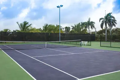a tennis court with a net and palm trees at Majestic Mirage Punta Cana, All Suites – All Inclusive in Punta Cana