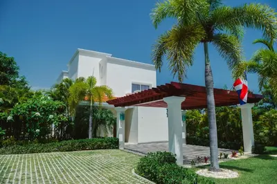 a villa with a palm tree and a house at Luxury Private Villas with Pool, Private Beach, BBQ in Punta Cana