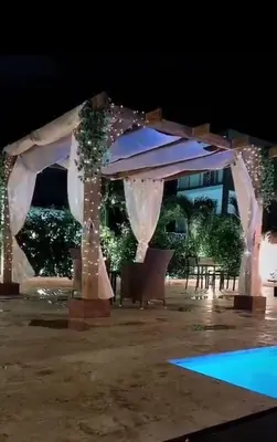 an outdoor wedding ceremony with a white arch and lights at Nuovo Hotel Playa Catalina in La Romana