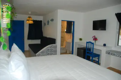 a bedroom with a white bed and a living room at Nuovo Hotel Playa Catalina in La Romana