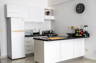 a kitchen with white cabinets and a white refrigerator at Lincoln Suite in Santo Domingo