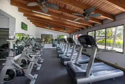 a gym with a row of treadmills and ceiling fans at Viva Dominicus Beach by Wyndham, A Trademark All Inclusive in Bayahibe