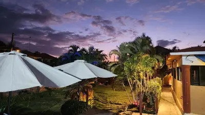 two white umbrellas sitting in a yard with trees at Hotel El Dorado in La Romana