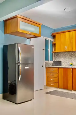 a kitchen with a stainless steel refrigerator and wooden cabinets at Hotel Casa Jum in Santiago de los Caballeros