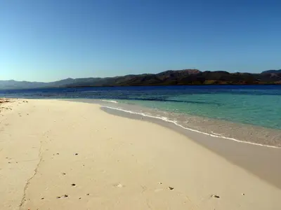 a sandy beach with the ocean and mountains in the background at Corales Punta Rusia in Punta Rucia