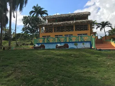 a building with benches in a park with palm trees at Casa Altea in Santa Bárbara de Samaná