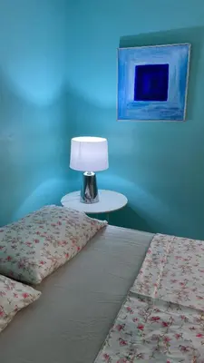 a bedroom with a bed with a lamp on a table at Casa Azul - Apartment in San Felipe de Puerto Plata