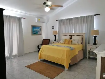 a bedroom with a bed with a yellow bedspread at Villas Del Jardin 7 in Juan Dolio