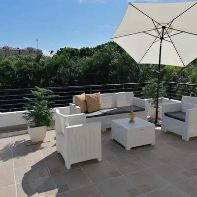 a patio with white furniture and an umbrella at Villas Del Jardin 7 in Juan Dolio