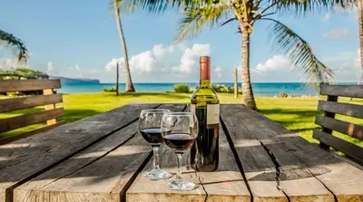 a bottle of wine and two glasses on a wooden table at Villa Ixora - Ocean Front in Las Galeras