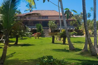 a house with palm trees in front of it at Jasmine La Playita - Ocean Front in Las Galeras
