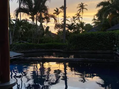 a pool with palm trees and a sunset in the background at Casa Barbara in Las Terrenas