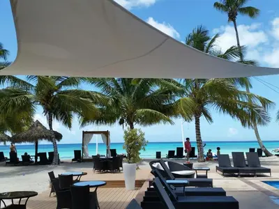 a beach with chairs and palm trees and the ocean at Appartamento Vista Mare in Bayahibe