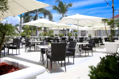 a restaurant with tables and white umbrellas at Bahia Principe Grand Aquamarine - Adults Only All Inclusive in Punta Cana