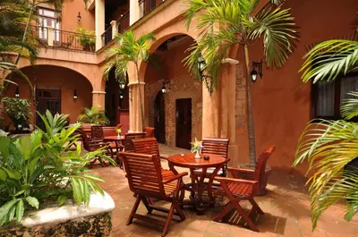 an outdoor patio with tables and chairs and palm trees at Boutique Hotel Palacio in Santo Domingo