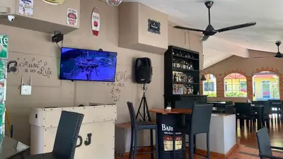 a restaurant with a bar with chairs and a tv on the wall at Hotel Don Andres in Sosúa