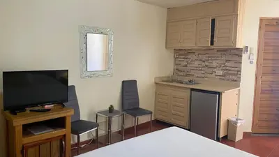 a living room with a tv and a kitchen with chairs at Hotel Don Andres in Sosúa