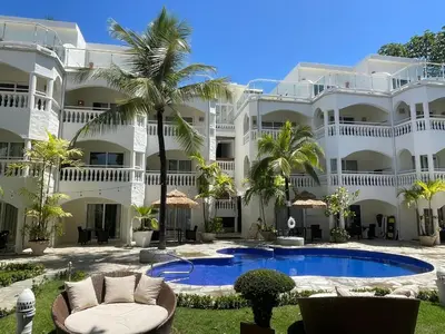 a large white building with a swimming pool and palm trees at Hotel Villa Taina in Cabarete