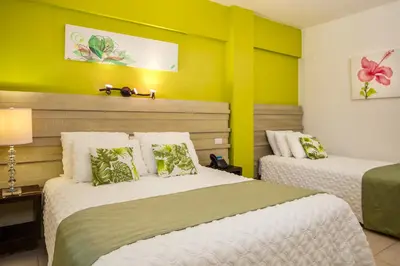 two beds in a room with green and yellow walls at Hotel Villa Taina in Cabarete