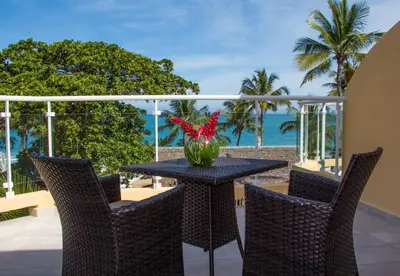 a table with chairs and a vase with red flowers on a balcony at Hotel Villa Taina in Cabarete