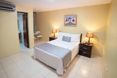 a bedroom with a bed and two night stands with lamps at Hotel Real Bella Vista in Santo Domingo