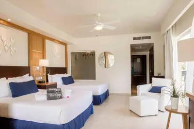 a hotel room with two beds and a couch at Ocean Blue & Sand Beach Resort - All Inclusive in Punta Cana