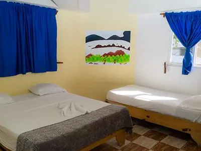 a bedroom with two beds and a window with blue curtains at Plaza Real Resort in Juan Dolio
