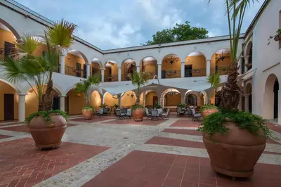 a courtyard of a building with palm trees and chairs at Hodelpa Nicolás de Ovando in Santo Domingo