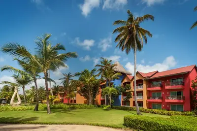 a resort with palm trees and a red building at Punta Cana Princess Adults Only - All Inclusive in Punta Cana