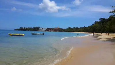 a beach with two boats in the water at Villa Mar Sosua in Sosúa