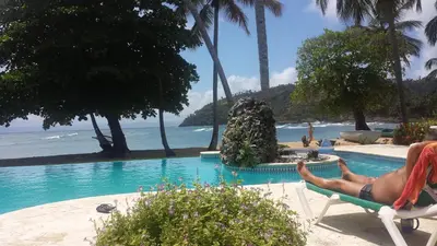 a man laying in a chair next to a swimming pool at The Cove Apartments in El Francés
