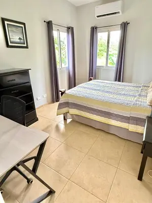 a bedroom with a bed and a table and windows at The Cove Apartments in El Francés