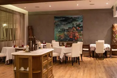 a dining room with white tables and chairs and a painting at Hotel Casa Hemingway in Juan Dolio