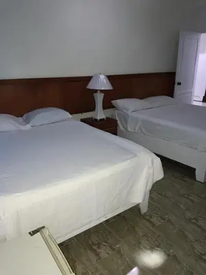 two beds in a bedroom with a lamp on a table at Hotel Costa Linda Beach Boca Chica in Boca Chica