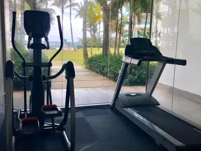 a gym with a treadmill and a window with palm trees at Seawinds Studio - Beachfront Getaway in Cabarete